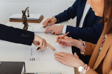 Hands signing a divorce decree, with a justice statue nearby, symbolizing legal proceedings.